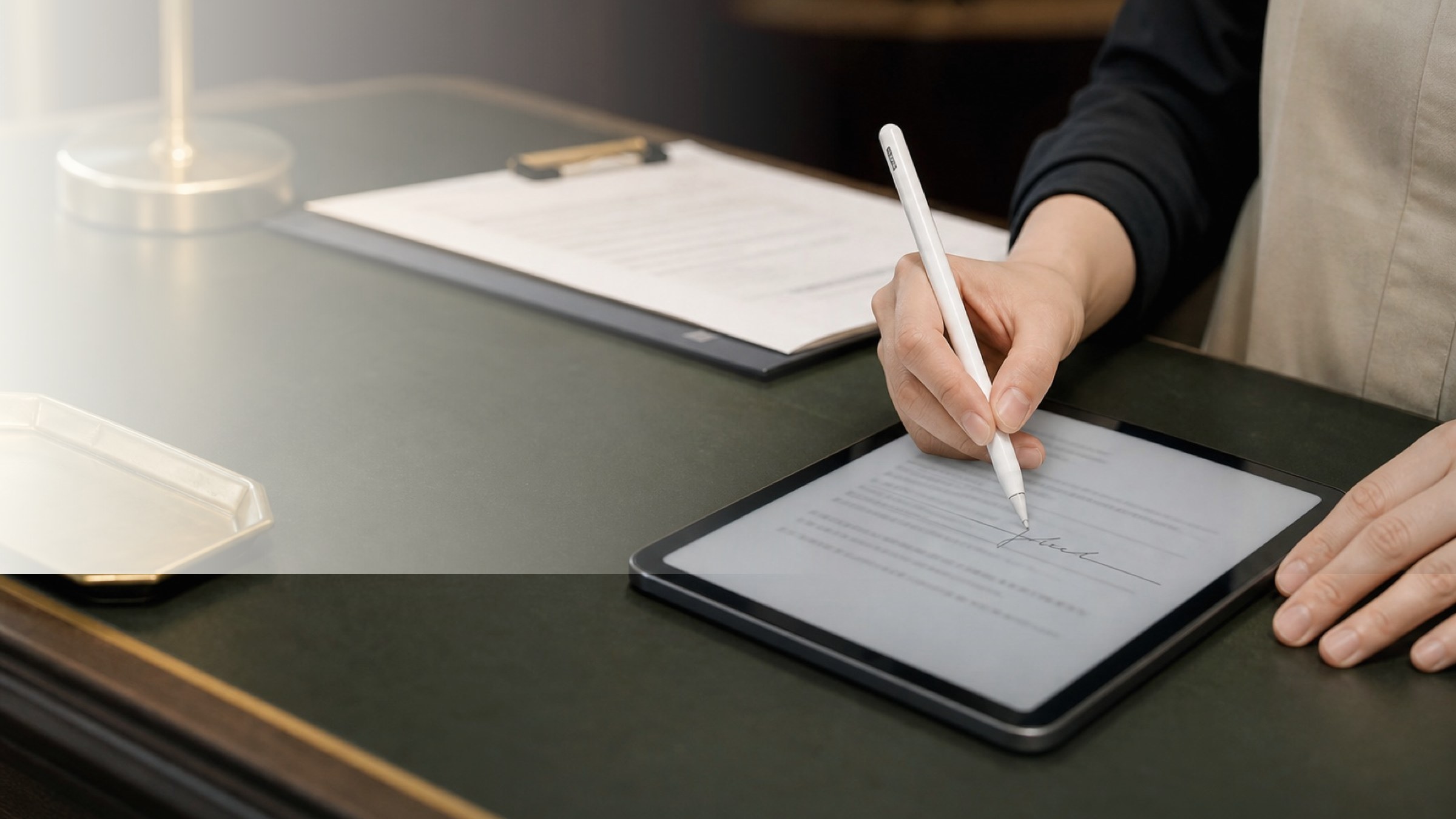 店舗のデスクでスタッフがタブレットの承諾書にサインしている手元